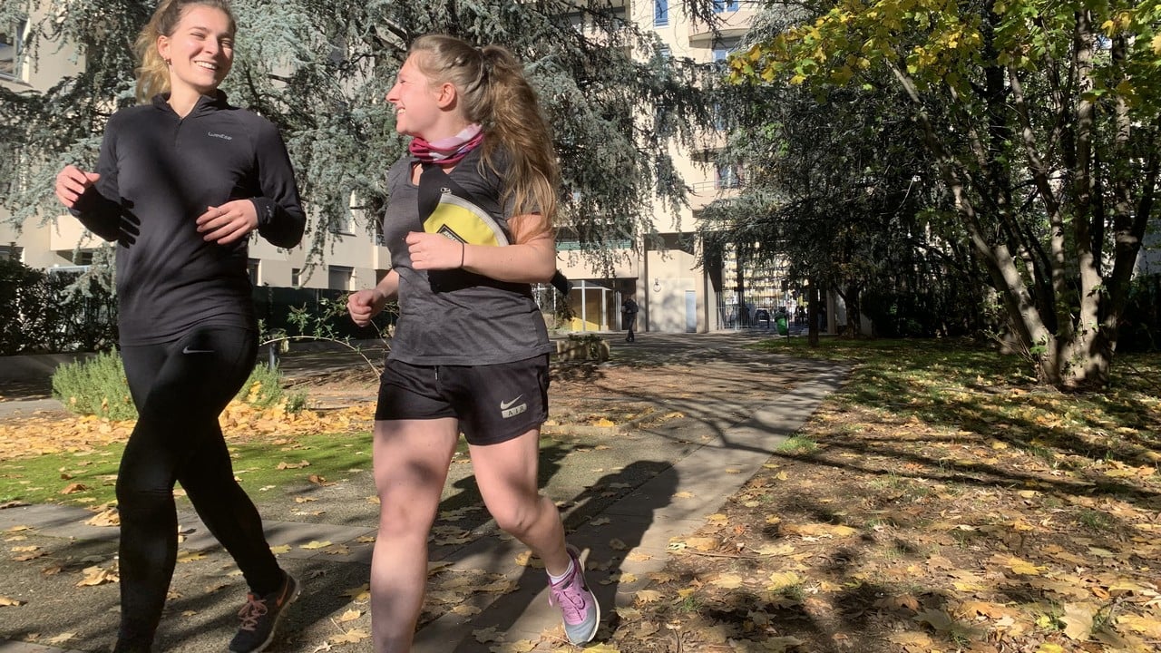 Dans un parc, deux jeunes femmes courent en riant.